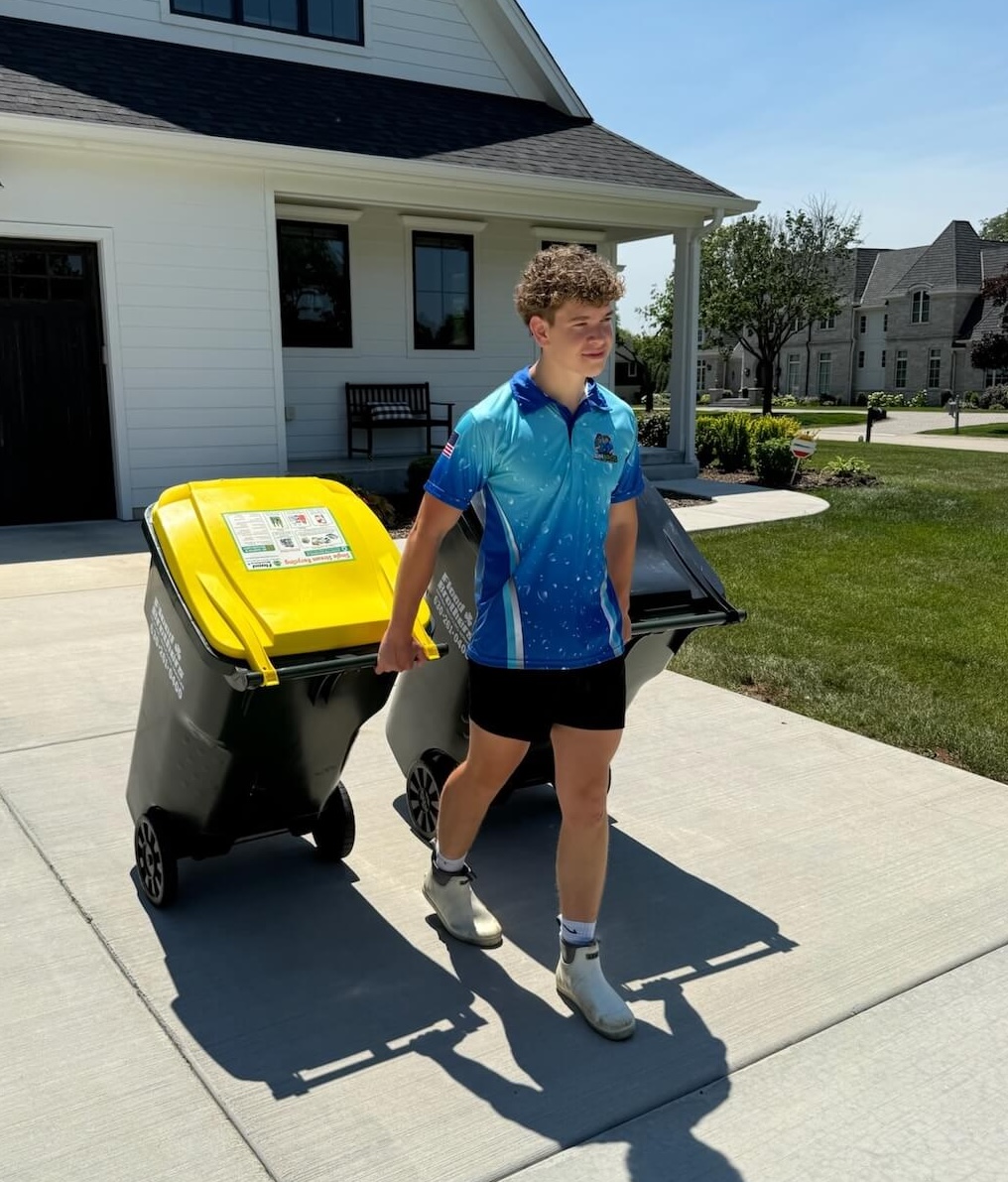 Bin Bros technician wheeling garbage and recycling cans to the curb for professional cleaning in Elmhurst, IL